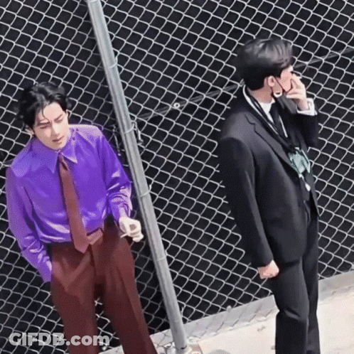 A Man In A Purple Shirt And Tie Is Standing Next To A Man In A Black Suit . GIF