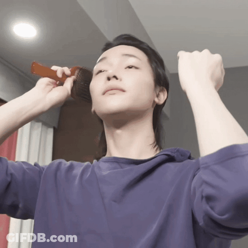A Man In A Purple Shirt Brushes His Hair With A Brush GIF