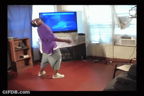 A Man In A Purple Shirt Is Dancing In Front Of A Flat Screen Television GIF