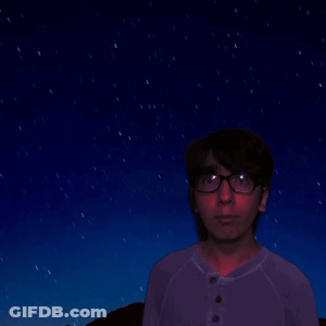 A Man In A Purple Shirt Is Looking At A Starry Night Sky GIF