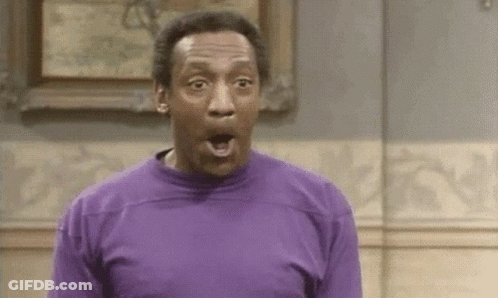 A Man In A Purple Shirt Is Making A Surprised Face In Front Of A Painting . GIF
