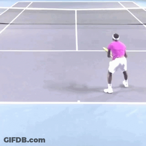 A Man In A Purple Shirt Is Playing Tennis On A Court GIF