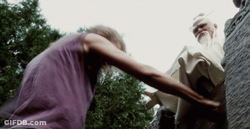 A Man In A Purple Shirt Is Reaching Out To Another Man GIF