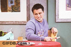 A Man In A Purple Shirt Is Sitting At A Table With A Glass Of Wine . GIF