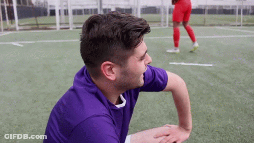 A Man In A Purple Shirt Is Sitting On The Field GIF