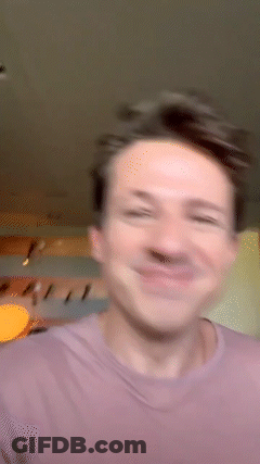 A Man In A Purple Shirt Is Smiling And Making A Funny Face GIF