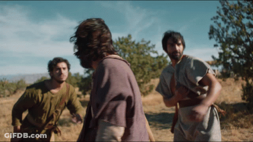 A Man In A Purple Shirt Is Standing In A Field With Other Men GIF