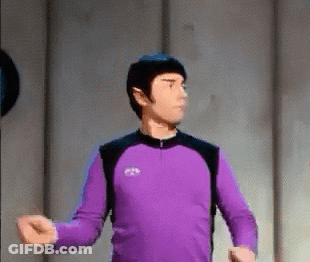 A Man In A Purple Shirt Is Standing In A Room With His Arms Outstretched GIF