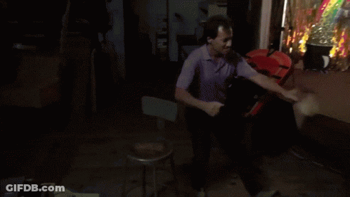A Man In A Purple Shirt Is Standing In Front Of A Clown Costume GIF