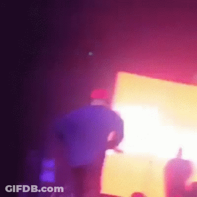 A Man In A Purple Shirt Is Standing In Front Of A Crowd At A Concert GIF
