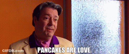 A Man In A Purple Shirt Is Standing In Front Of A Window And Says Pancakes Are Love . GIF