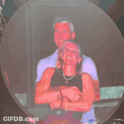 A Man In A Purple Shirt Is Standing Next To A Woman In A Pink Shirt GIF