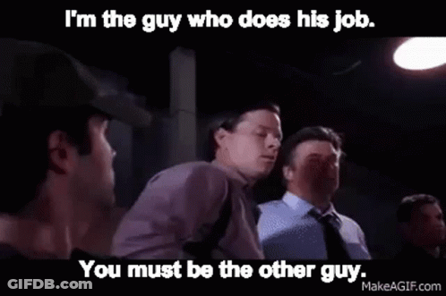 A Man In A Purple Shirt Is Talking To Another Man In A Dark Room . GIF