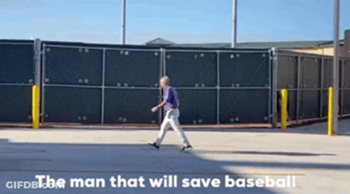 A Man In A Purple Shirt Is Walking Down A Street With The Words " The Man That Will Save Baseball " Written Below Him GIF