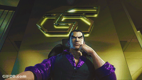 A Man In A Purple Shirt Sits In A Chair In Front Of A Large 5 GIF