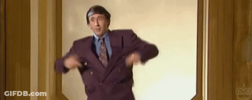 A Man In A Purple Suit And Tie Is Standing In A Doorway And Dancing . GIF