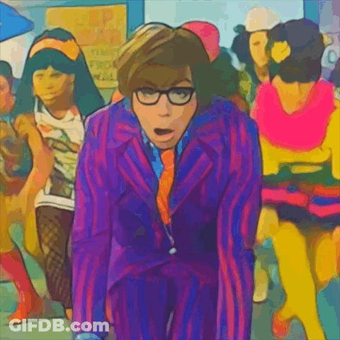 A Man In A Purple Suit And Tie Stands In Front Of A Crowd Of People GIF