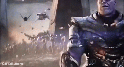 A Man In A Purple Suit Is Standing In Front Of A Crowd Of People With Planes Flying In The Background GIF
