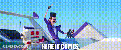 A Man In A Purple Suit Is Standing Next To A Robot And The Words Here It Comes GIF