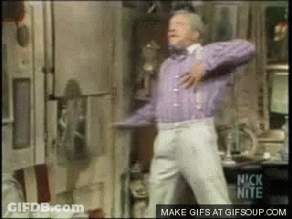A Man In A Purple Sweater And White Pants Is Dancing In A Room With A Nick Nite Logo In The Corner GIF
