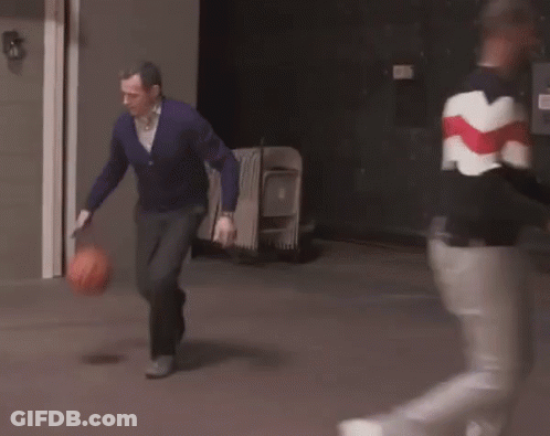 A Man In A Purple Sweater Is Running With A Basketball In His Hands . GIF