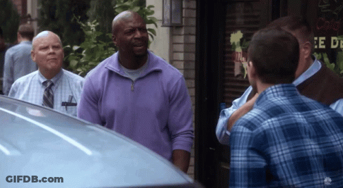 A Man In A Purple Sweater Is Standing In Front Of A Sign That Says " E De " GIF