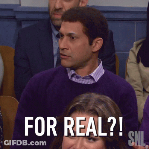 A Man In A Purple Sweater Sits In Front Of A Sign That Says " What The Hell Is That Snl " GIF
