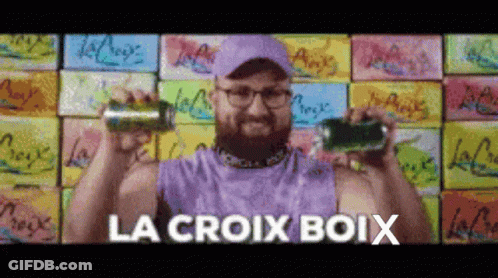 A Man In A Purple Tank Top Is Holding Two Cans Of Soda And The Words La Croix Boix Are Above Him GIF
