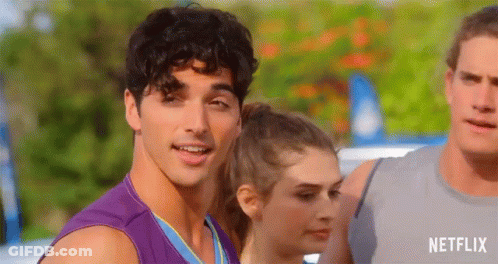 A Man In A Purple Tank Top Is Smiling While Standing Next To A Woman And A Man . GIF