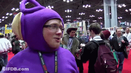 A Man In A Purple Teletubbies Costume Is Standing In A Crowd GIF