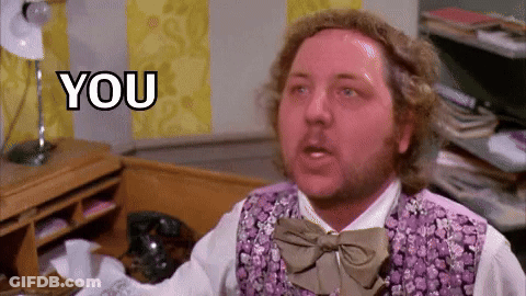A Man In A Purple Vest And Bow Tie Is Sitting In Front Of A Desk . GIF