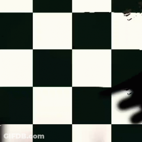 A Man In A Purple Vest Is Smiling In Front Of A Black And White Checkered Background GIF
