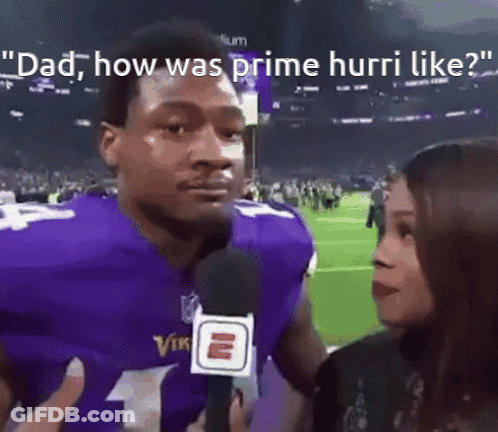 A Man In A Purple Vikings Jersey Is Being Interviewed By A Woman . GIF