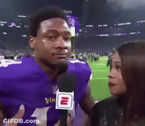 A Man In A Purple Vikings Jersey Is Being Interviewed By A Woman Holding A Microphone . GIF
