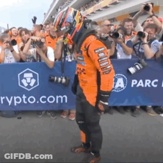 A Man In A Race Suit Is Standing In Front Of A Sign That Says " Rypto.com " GIF