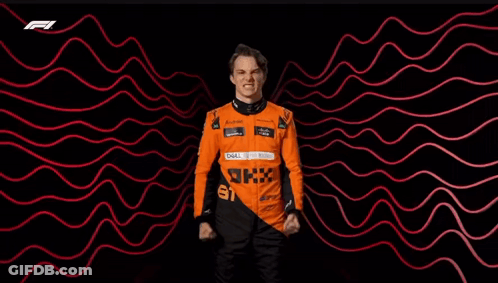 A Man In A Racing Suit Is Standing In Front Of A Red And Black Background . GIF