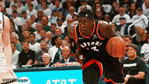 A Man In A Raptors Jersey Dribbles A Basketball In Front Of A Crowd GIF