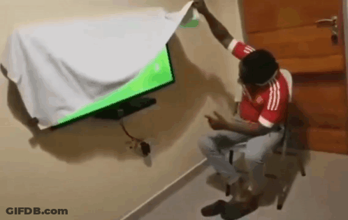 A Man In A Red Adidas Shirt Is Sitting In Front Of A Television GIF