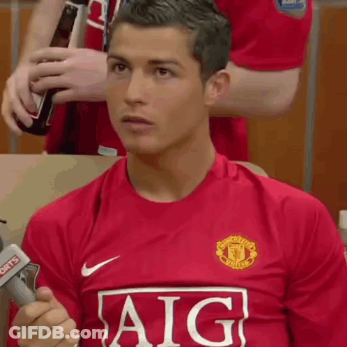 A Man In A Red Aig Jersey Is Holding A Microphone . GIF