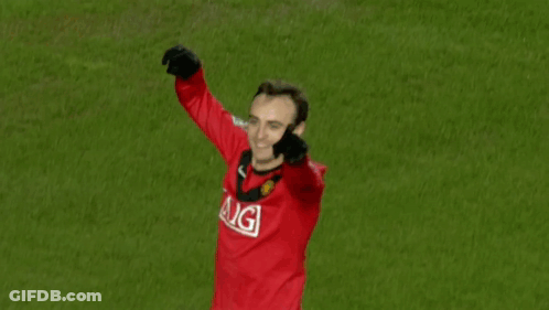 A Man In A Red Aig Jersey Stands On A Green Field GIF