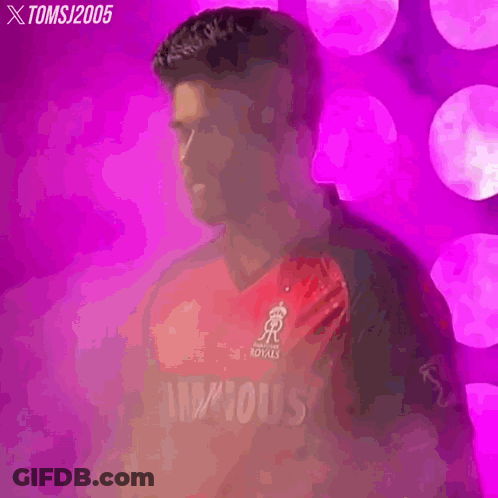 A Man In A Red And Black Cricket Jersey Is Standing In Front Of A Pink Background . GIF