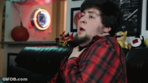 A Man In A Red And Black Plaid Shirt Is Sitting On A Couch In Front Of A Pepsi Sign GIF