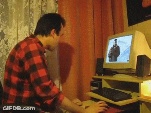 A Man In A Red And Black Plaid Shirt Is Typing On A Keyboard In Front Of A Computer Monitor . GIF