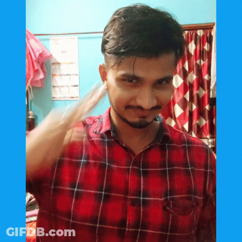 A Man In A Red And Black Plaid Shirt Stands In Front Of A Blue Wall With A Calendar On It GIF