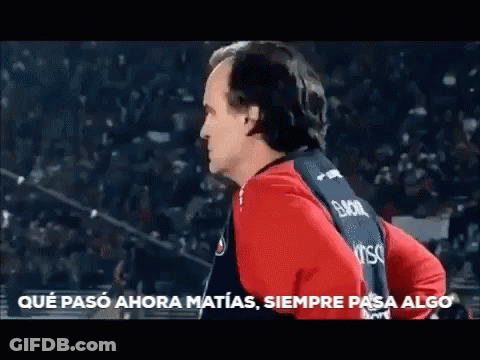 A Man In A Red And Black Shirt Is Standing In Front Of A Crowd And Says Que Paso Ahora Matias Siempre Pasa Algo GIF