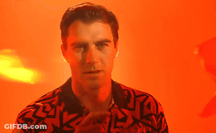 A Man In A Red And Black Shirt Is Standing In Front Of An Orange Background . GIF