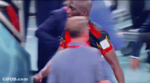 A Man In A Red And Black Shirt With The Letter A On It Is Standing Next To Another Man GIF