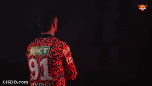 A Man In A Red And Black Shirt With The Name Howzzat GIF