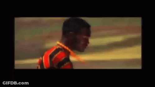 A Man In A Red And Black Striped Shirt Is Holding A Sword . GIF