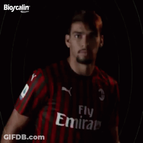 A Man In A Red And Black Striped Shirt Is Standing In Front Of A Black Background With The Word Paqueta Written On It . GIF